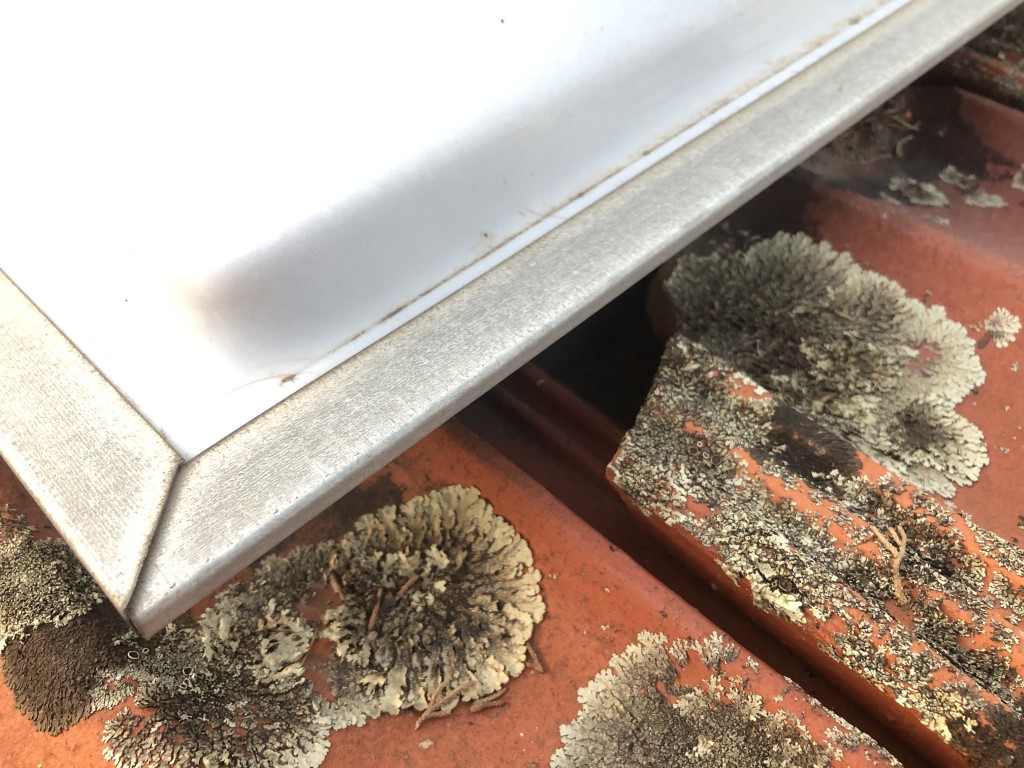 Chipped tile behind a skylight in a tiled roof